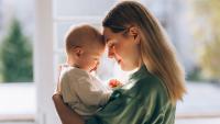 A mother holding a baby with its forehead touching her forehead